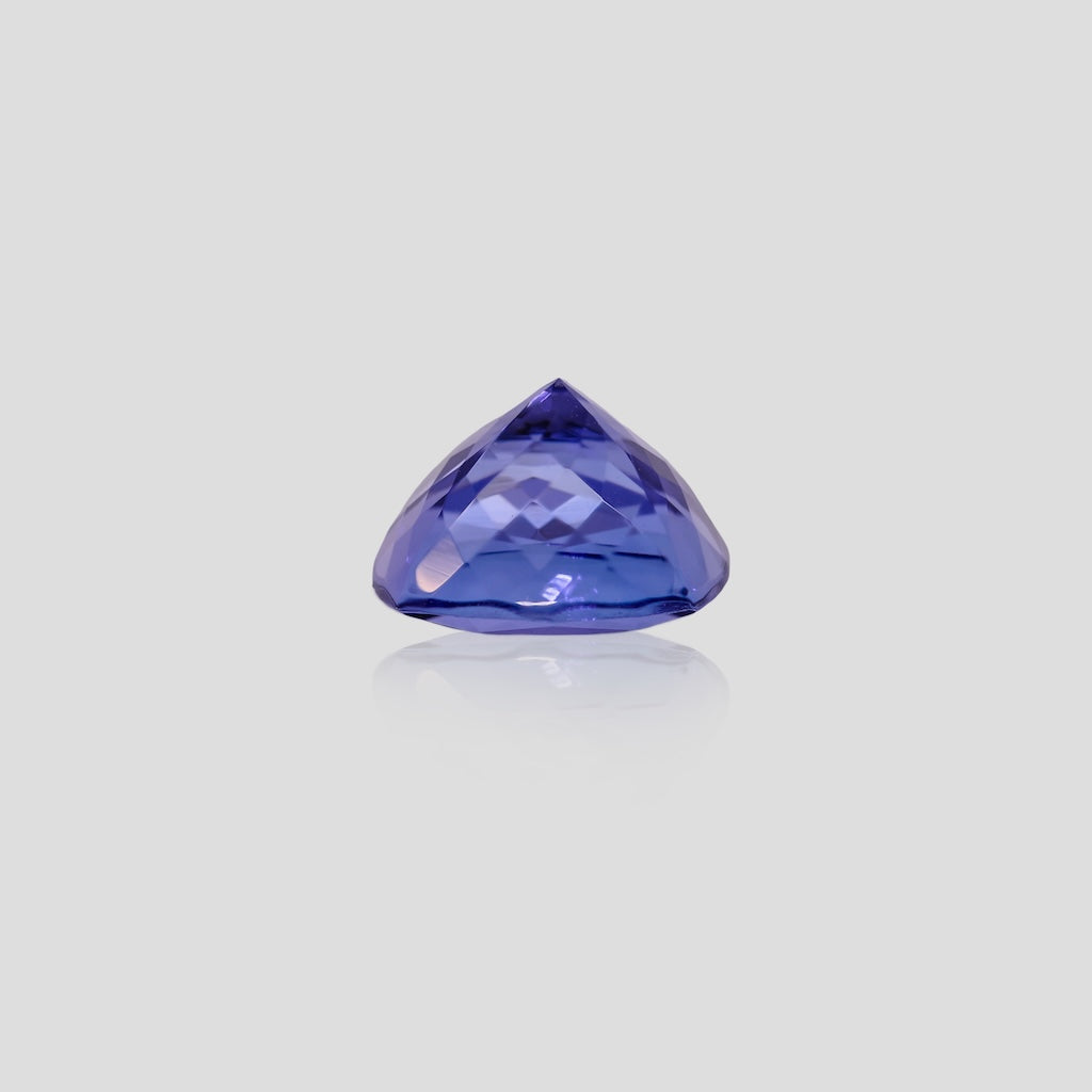 cushion shaped blue tanzanite gemstone on a light gray background