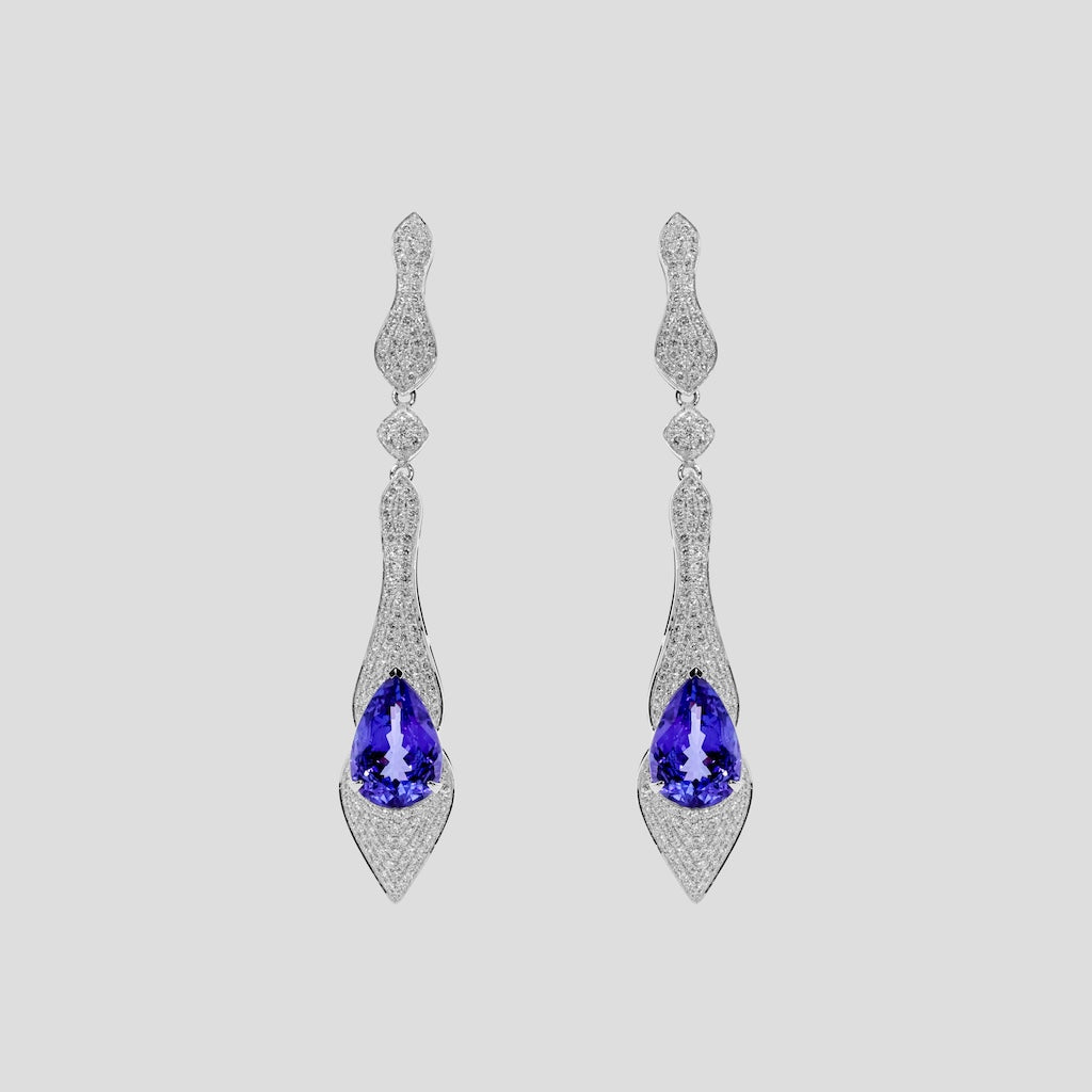 Pair of gold earrings with tanzanite blue gemstones and diamonds  on a light gray background