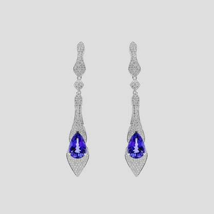 Pair of gold earrings with tanzanite blue gemstones and diamonds  on a light gray background