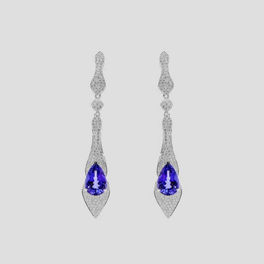 Pair of gold earrings with tanzanite blue gemstones and diamonds  on a light gray background