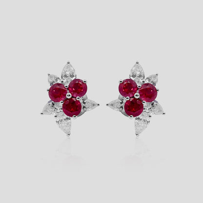 Pair of earrings with ruby red gemstones and diamond on a light gray background