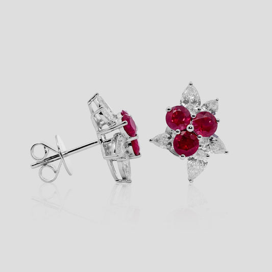 Pair of earrings with ruby red gemstones and diamonds on a light gray background