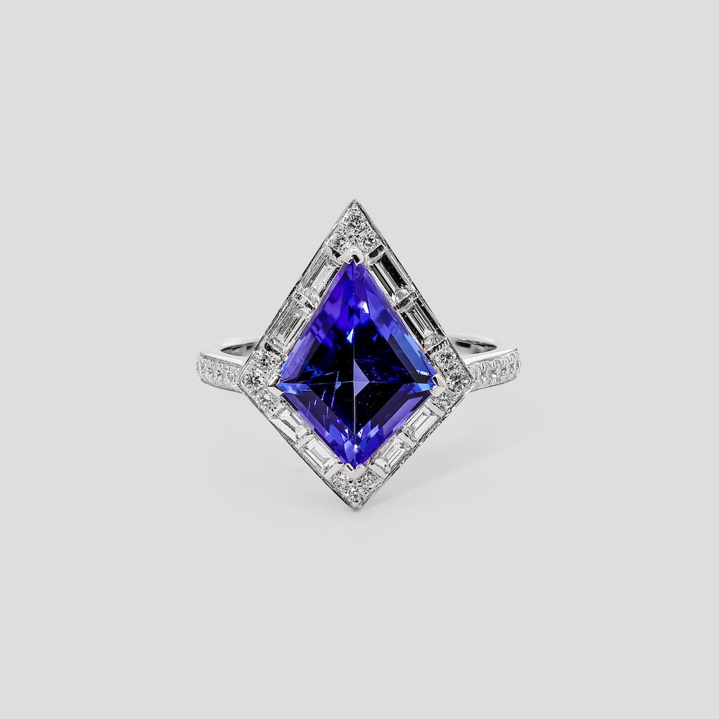 Ring with a kite tanzanite gemstone and diamond accents on a light gray background