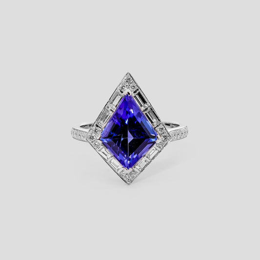 Ring with a kite tanzanite gemstone and diamond accents on a light gray background