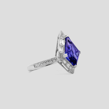 Ring with a kite shaped tanzanite gemstone and diamond accents on a light gray background
