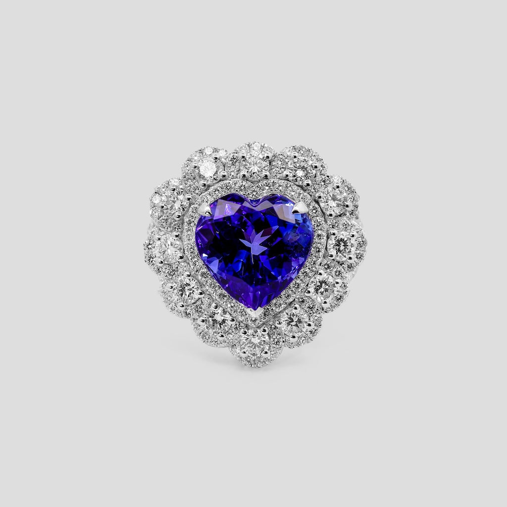 Heart-shaped tanzanite ring with diamond accents on a light gray background