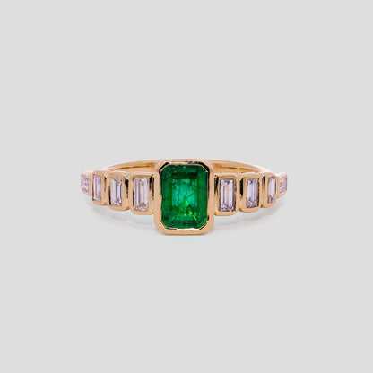 Gold ring with emerald green stone and smaller diamonds on a light gray background