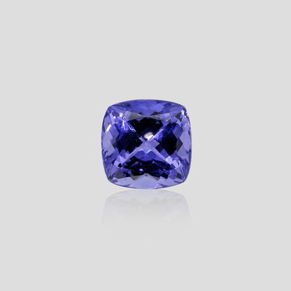 Cushion-shaped tanzanite blue gemstone on a light gray background
