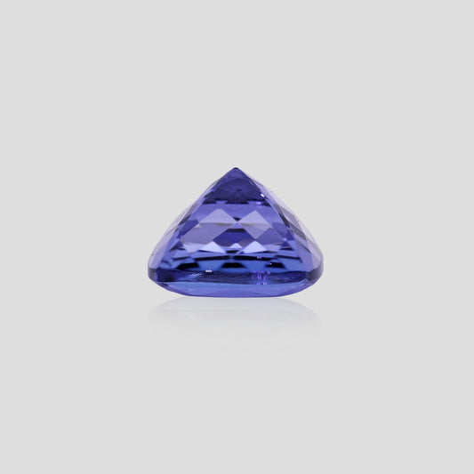 Cushion-shaped tanzanite purple gemstone on a light gray background