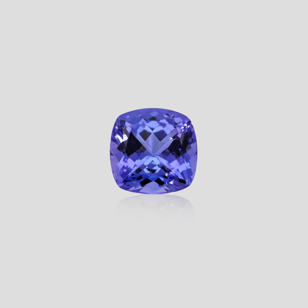 Cushion-shaped blue tanzanite gemstone on a light gray background