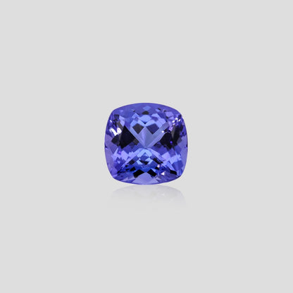 Cushion-shaped blue tanzanite gemstone on a light gray background