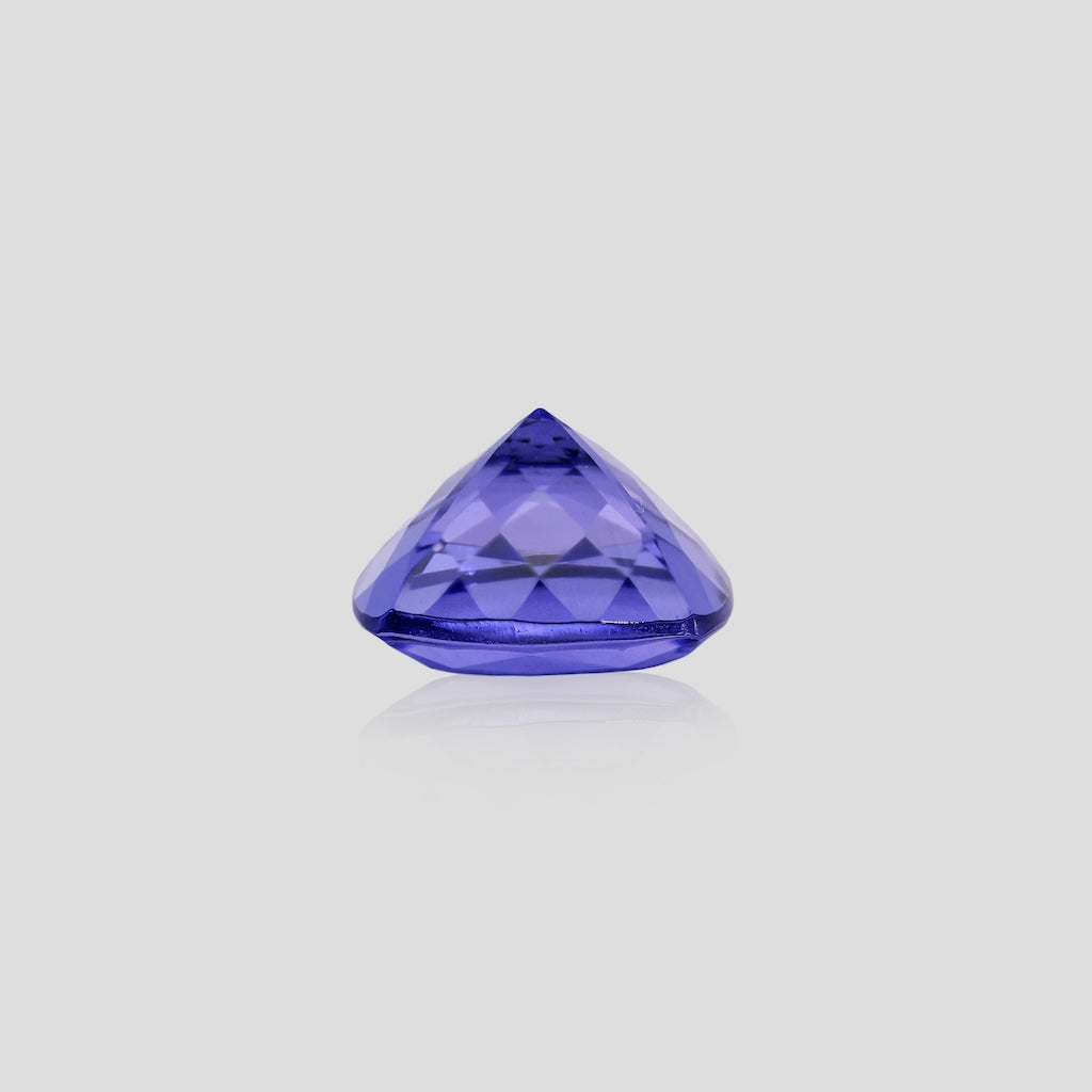 cushion-shaped blue tanzanite gemstone on a light gray background