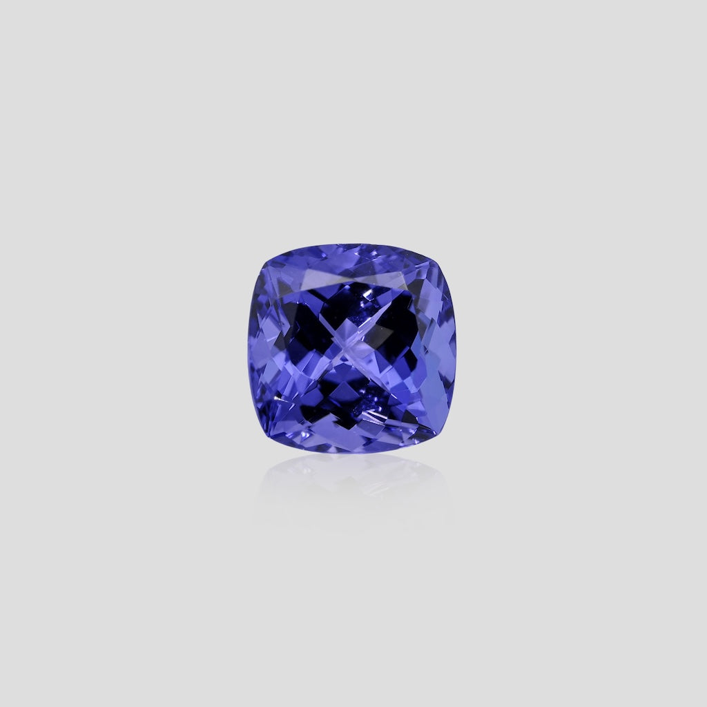 Cushion-shaped tanzanite blue purple gemstone on a light gray background