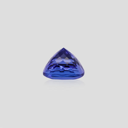 Trillion-shaped tanzanite blue gemstone on a light gray background