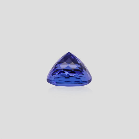 Trillion-shaped tanzanite blue gemstone on a light gray background