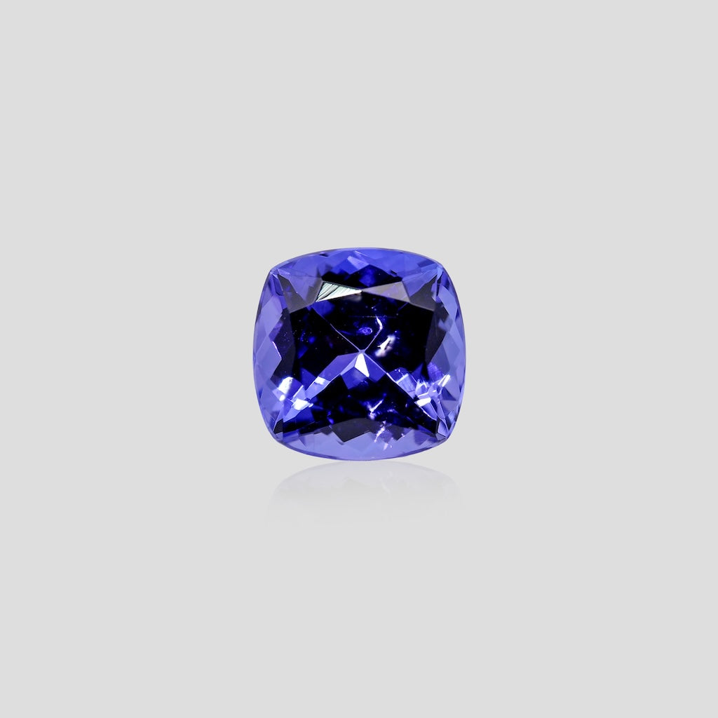 Cushion-cut blue tanzanite gemstone on a light gray background