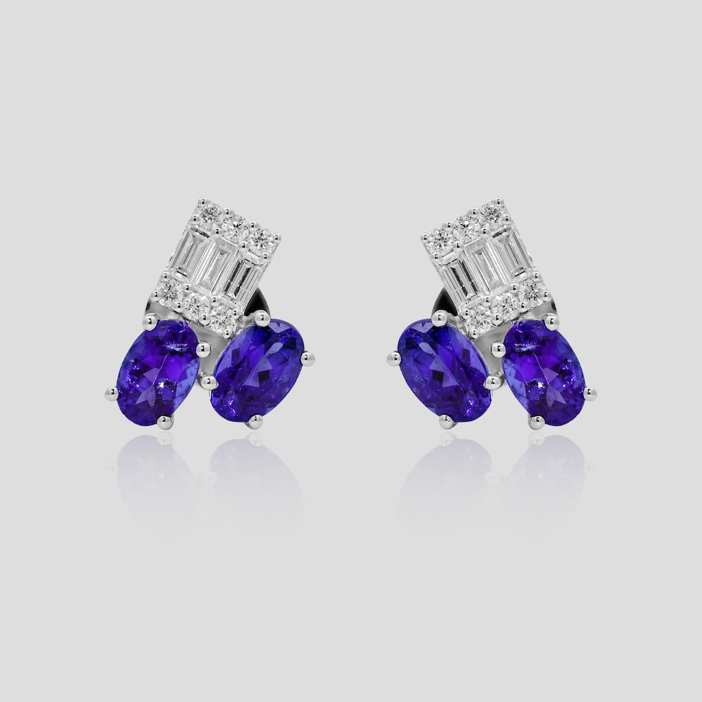 Pair of earrings with blue tanzanite stones and diamond accents on a light gray background