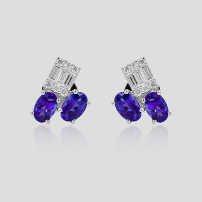 Pair of earrings with blue tanzanite stones and diamond accents on a light gray background