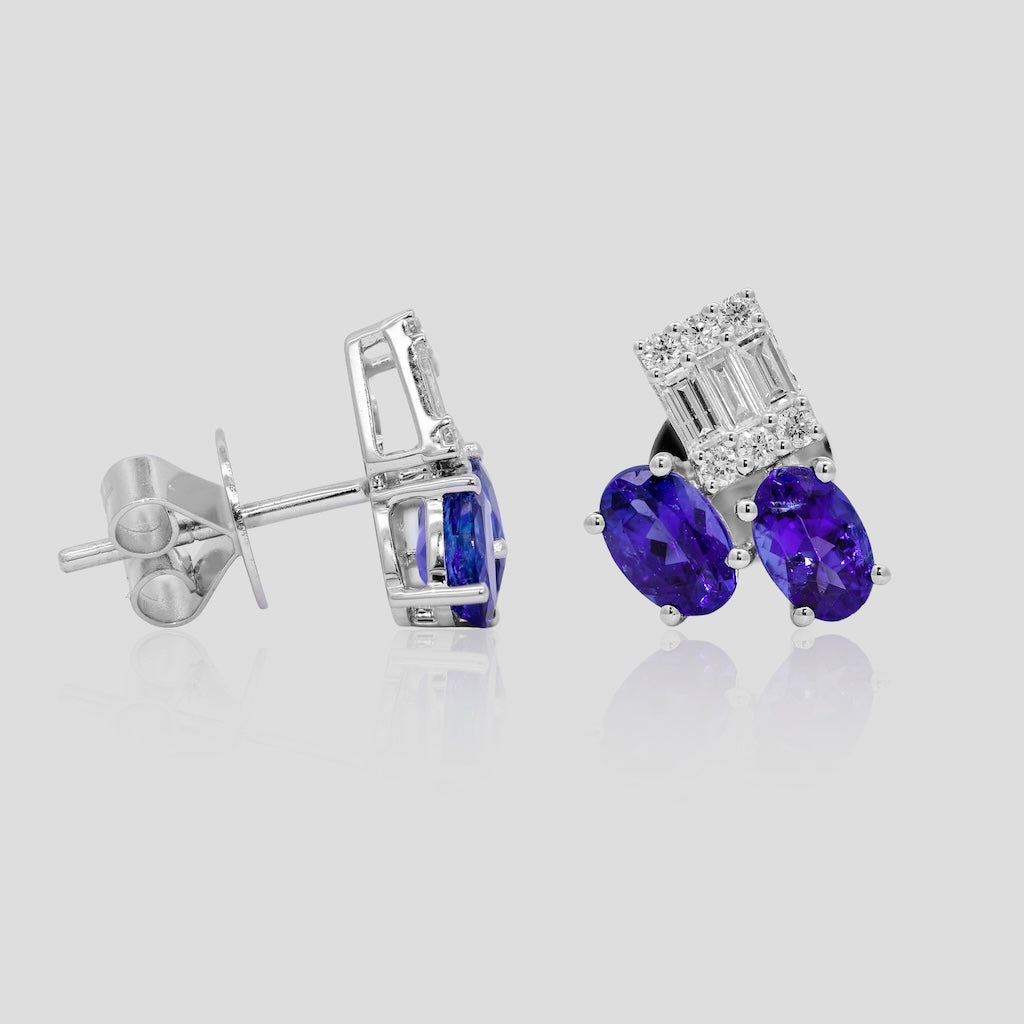Pair of white gold earrings with tanzanite gemstones on a light gray background