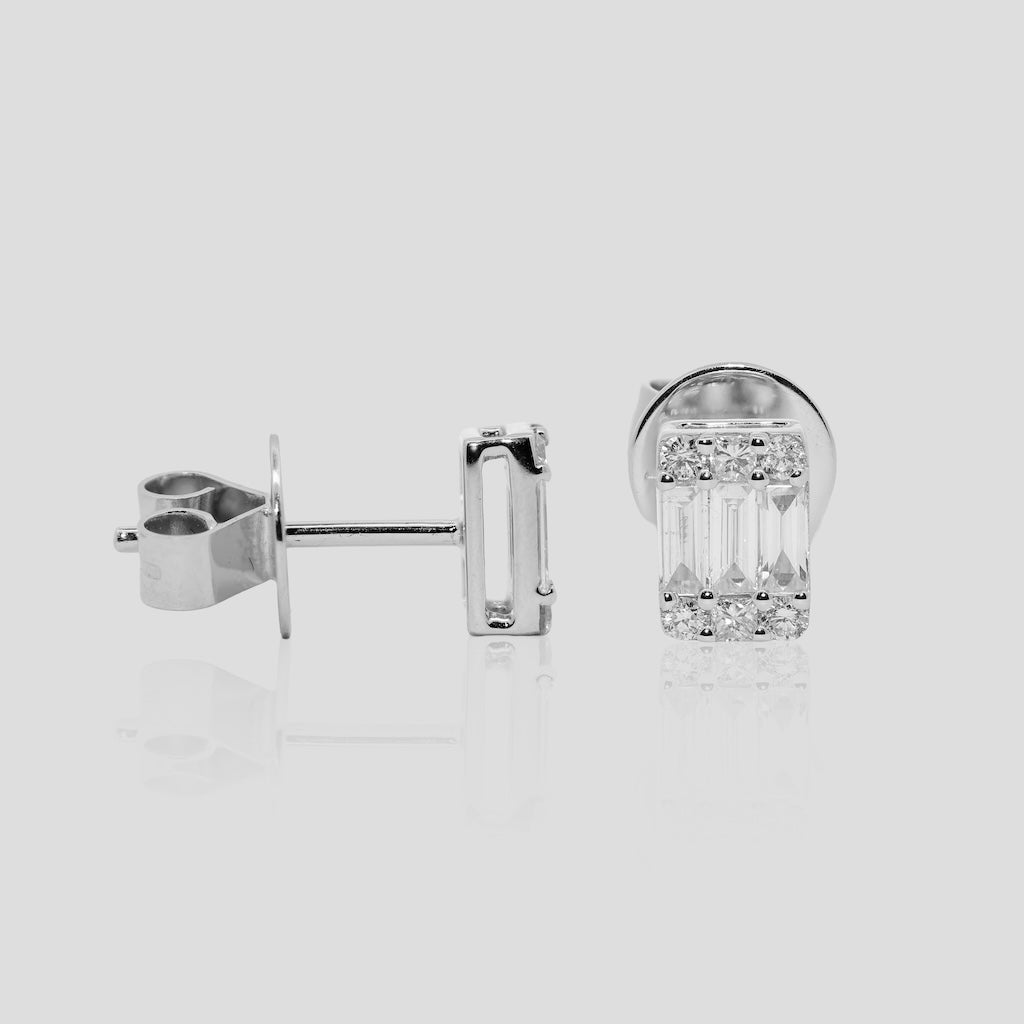 Pair of baguette diamond earrings in white gold on a light gray background