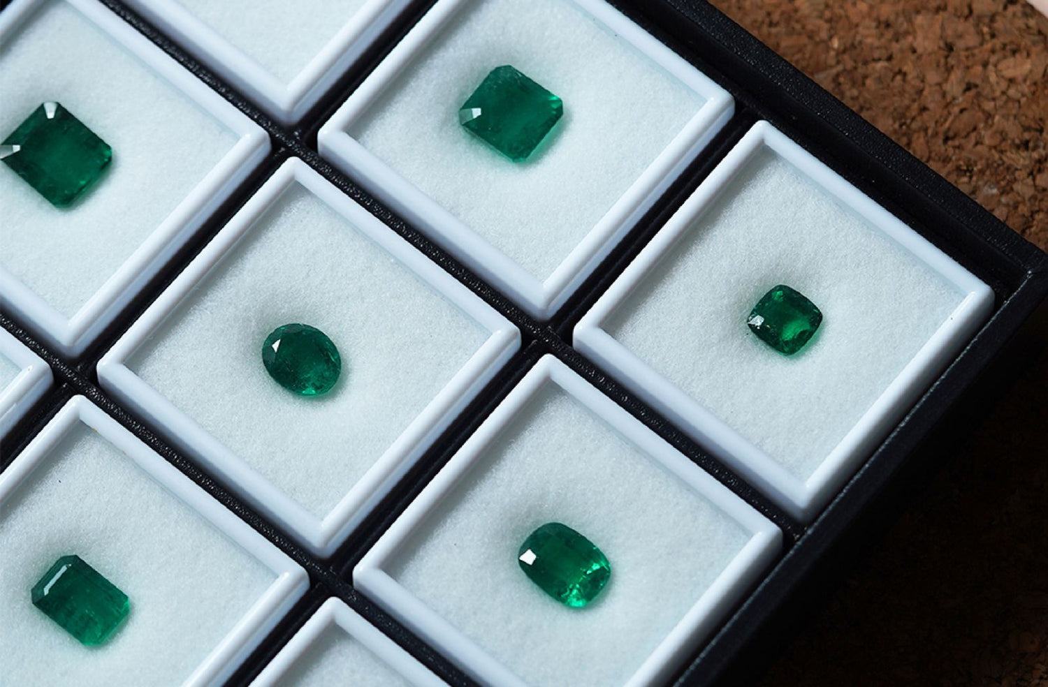 emerald gemstones in a display case with white separators