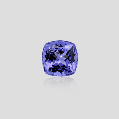 Cushion-shaped blue tanzanite gemstone on a light gray background