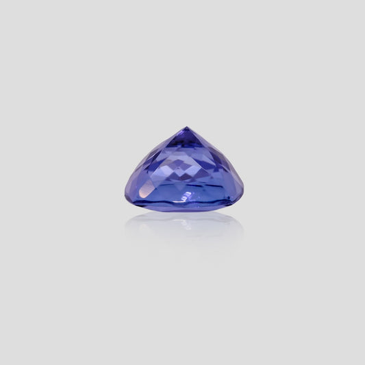 cushion shaped blue tanzanite gemstone on a light gray background