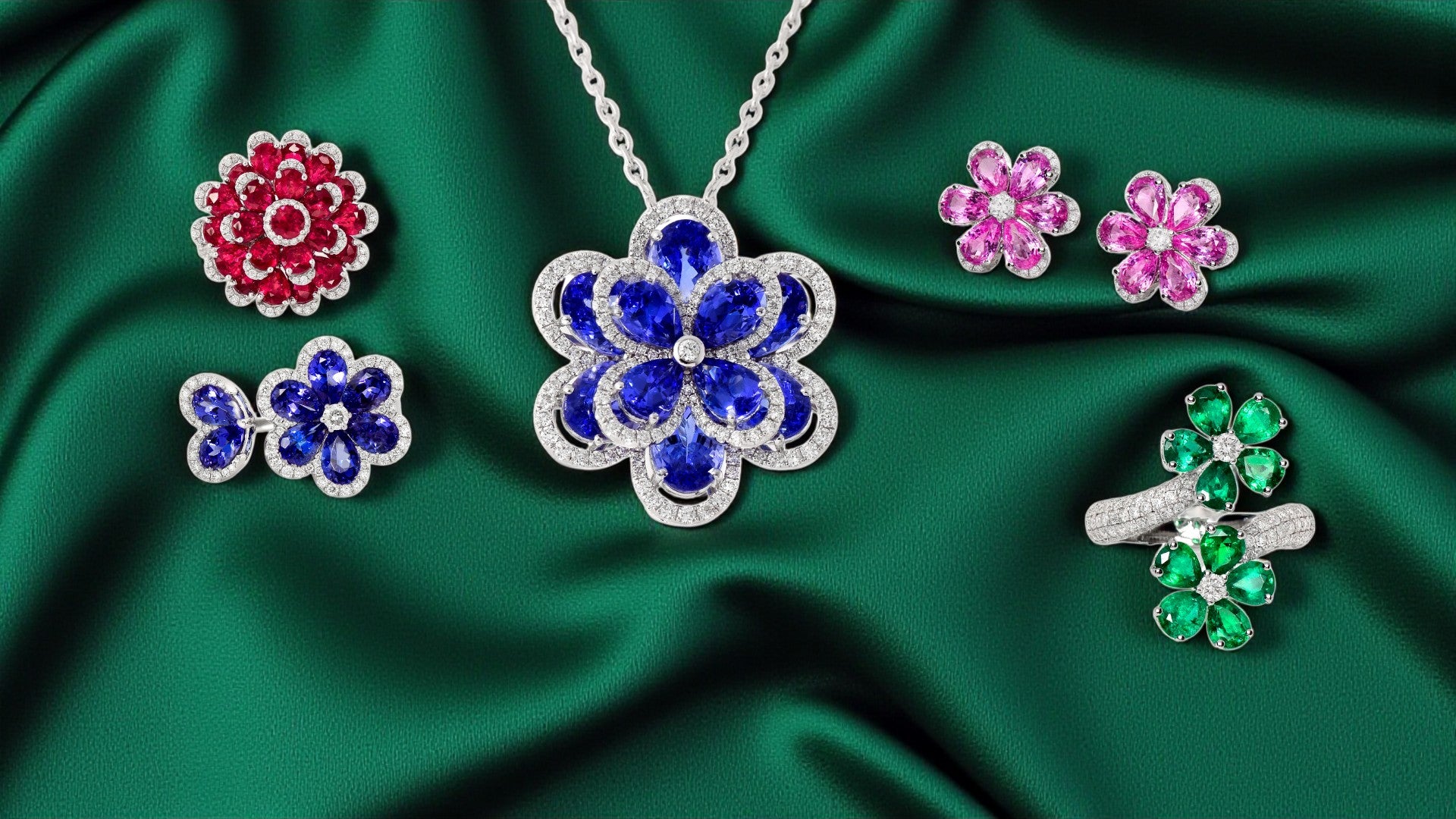 Floral jewelry with blue, red, and green stones on a green fabric background